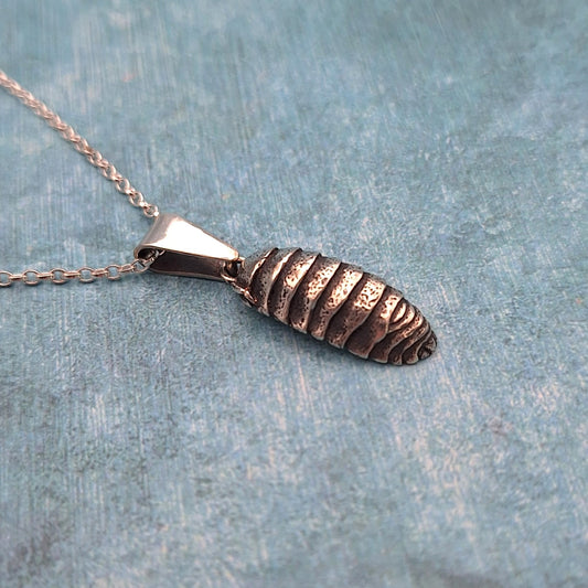 A photo of a realistic silver sculpture of a woodlouse, attached to a chain as a piece of jewellery, on a mottled blue background.