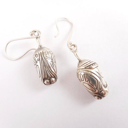 A photo of a pair of silver chrysalis earrings on a white background.