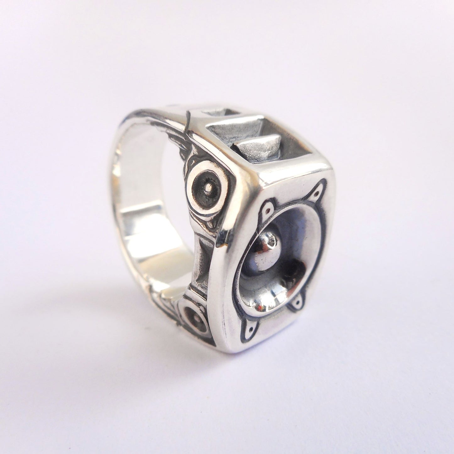 A photo of a chunky silver ring shaped like a soundsystem.